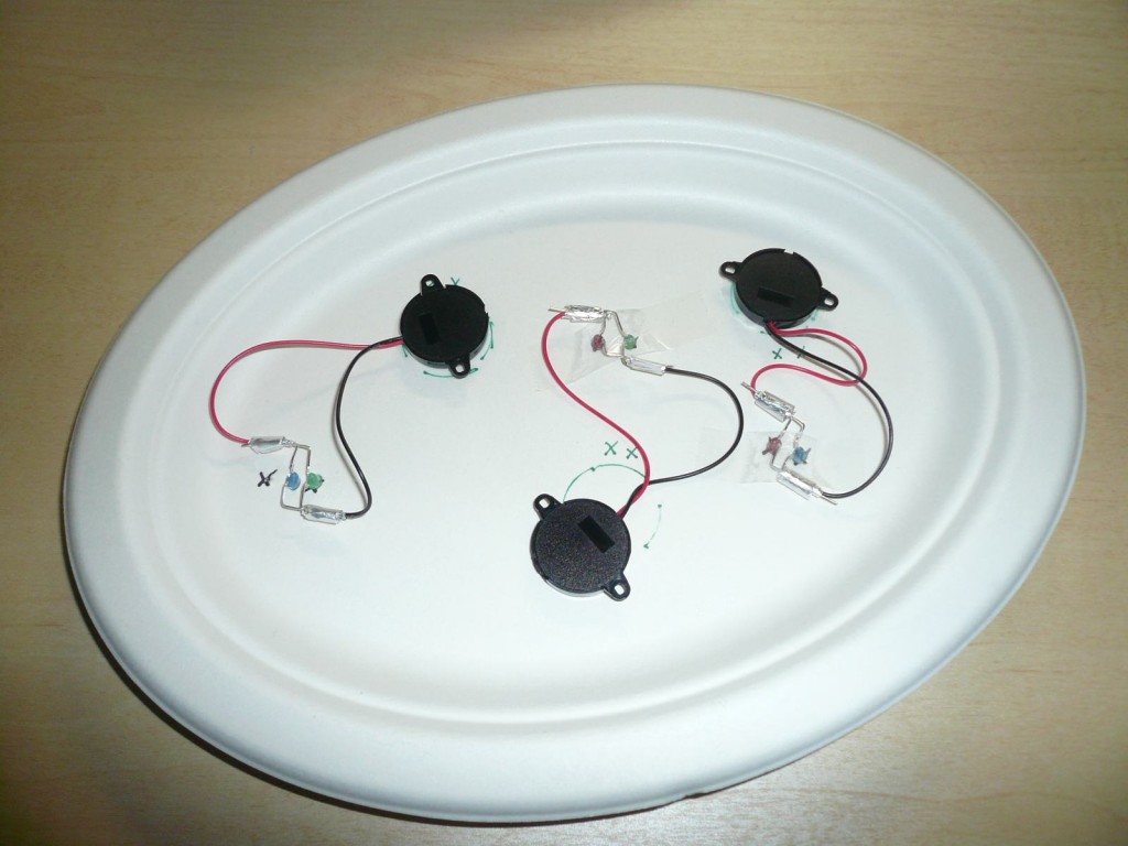 紙皿の裏側　圧電素子が発光ダイオードと繋がっており、紙皿を叩く力をひろって発光させます